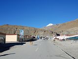 42 Main Street In Darchen Tibet With Mount Kailash Behind The main street in Darchen (4681m) stretches uphill with Mount Kailash poking up above the horizon ridge.